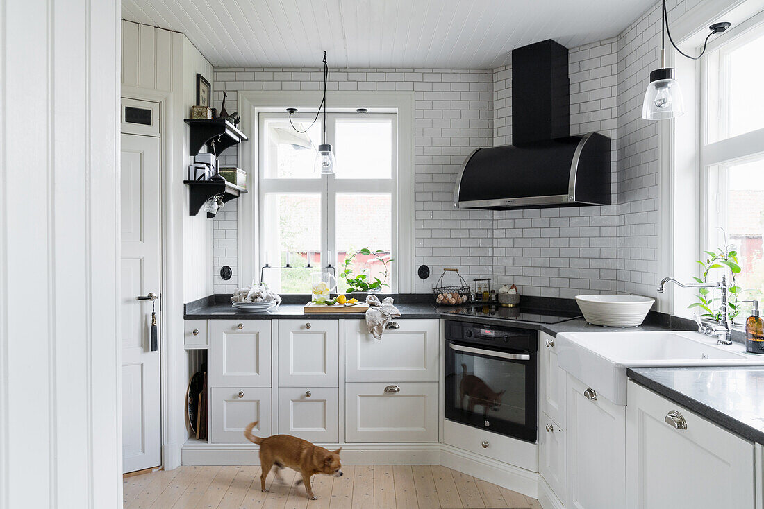 White fitted kitchen with black worktop and extractor hood