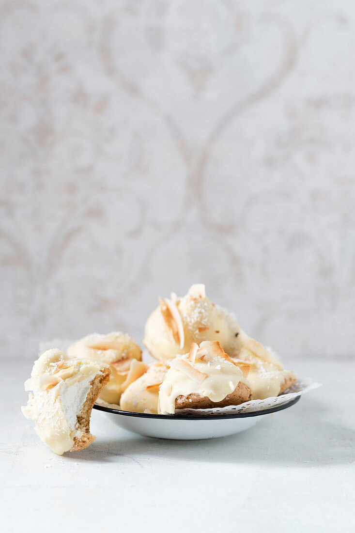Homemade foam kisses with white chocolate and coconut shavings on a biscuit base