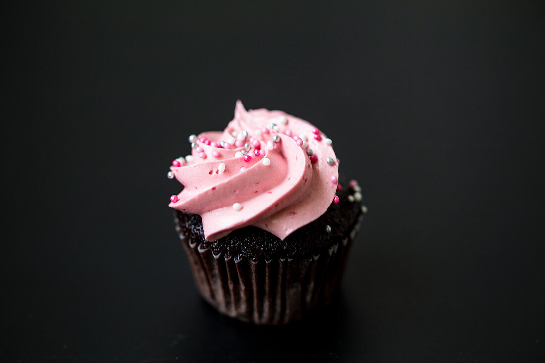 A chocolate cupcake with raspberry cream and sugar sprinkles