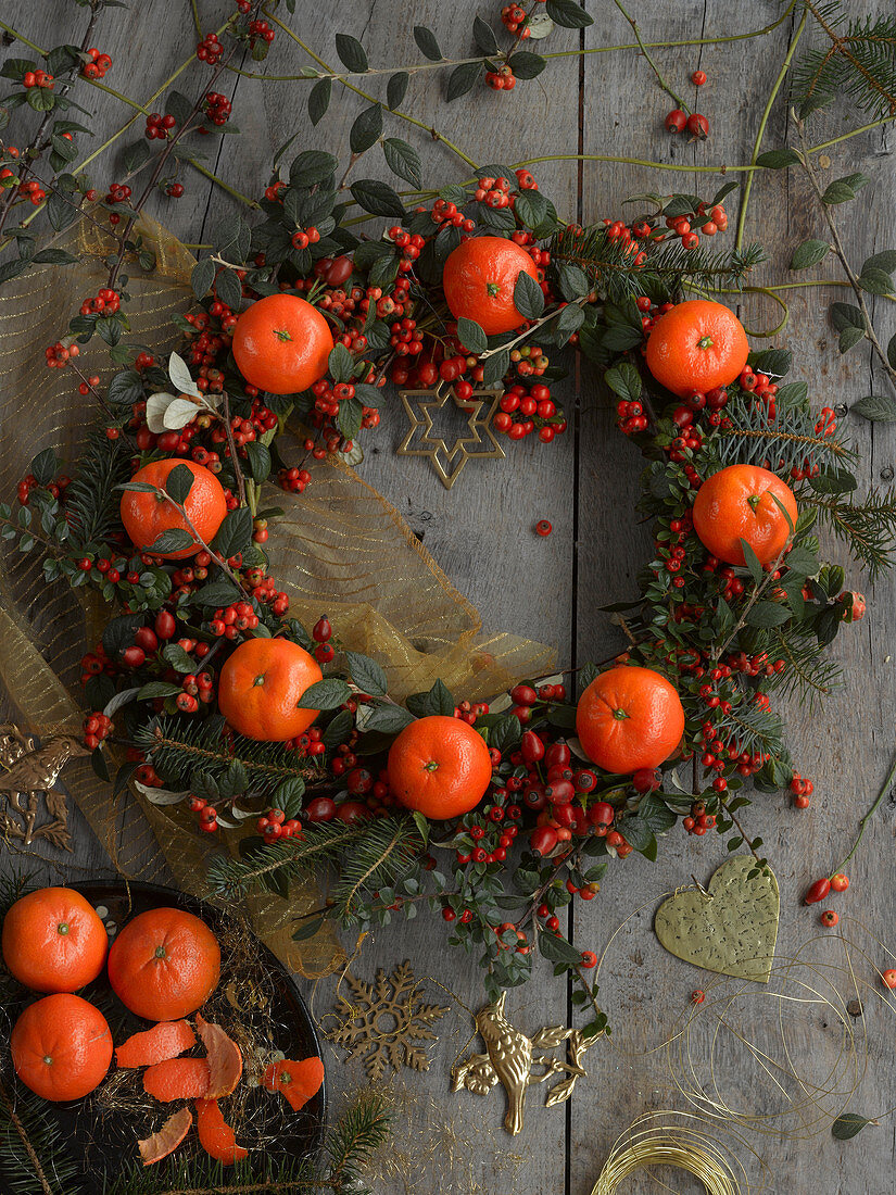 Wreath of cotoneaster berries, rose hips, spruce branches and tangerines
