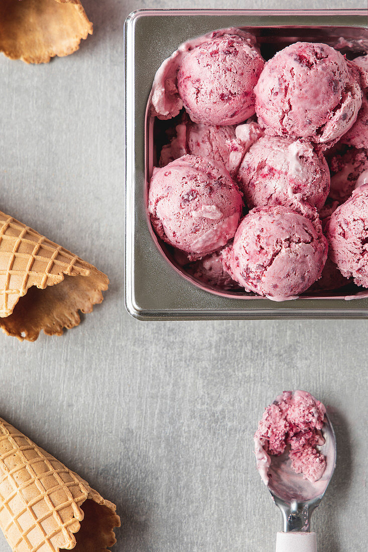 Homemade cherry ice cream scoops arranged on table with waffle cones