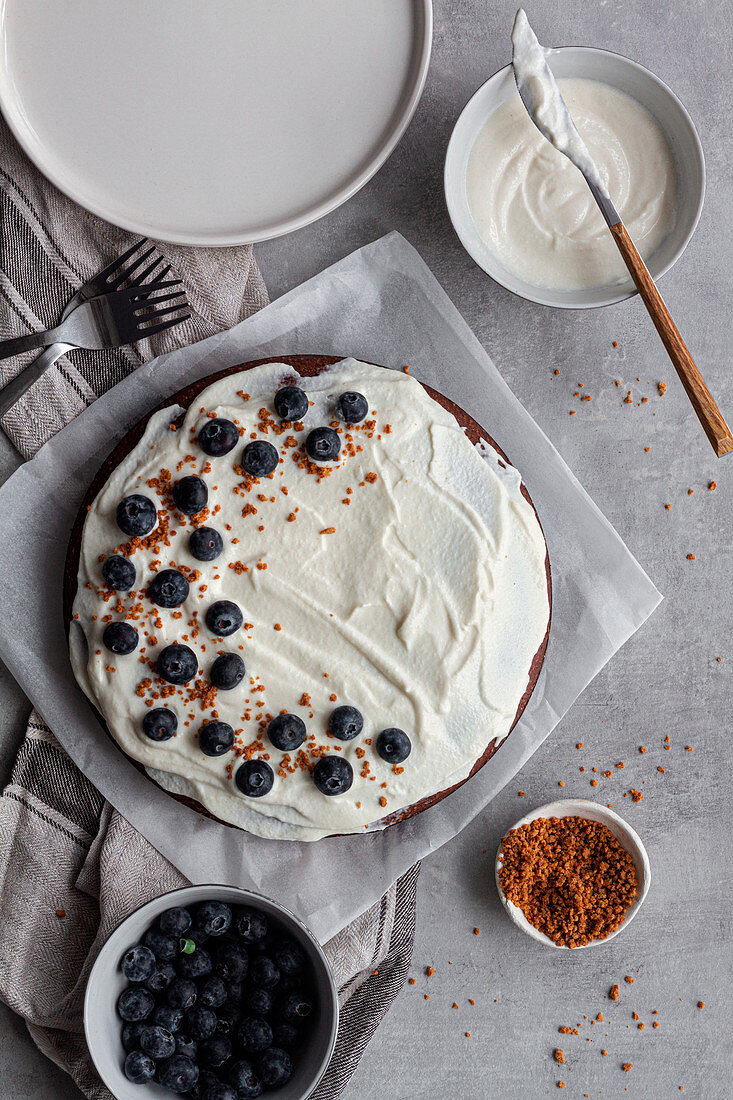 Homemade chocolate cake decorated with white cream and blueberries