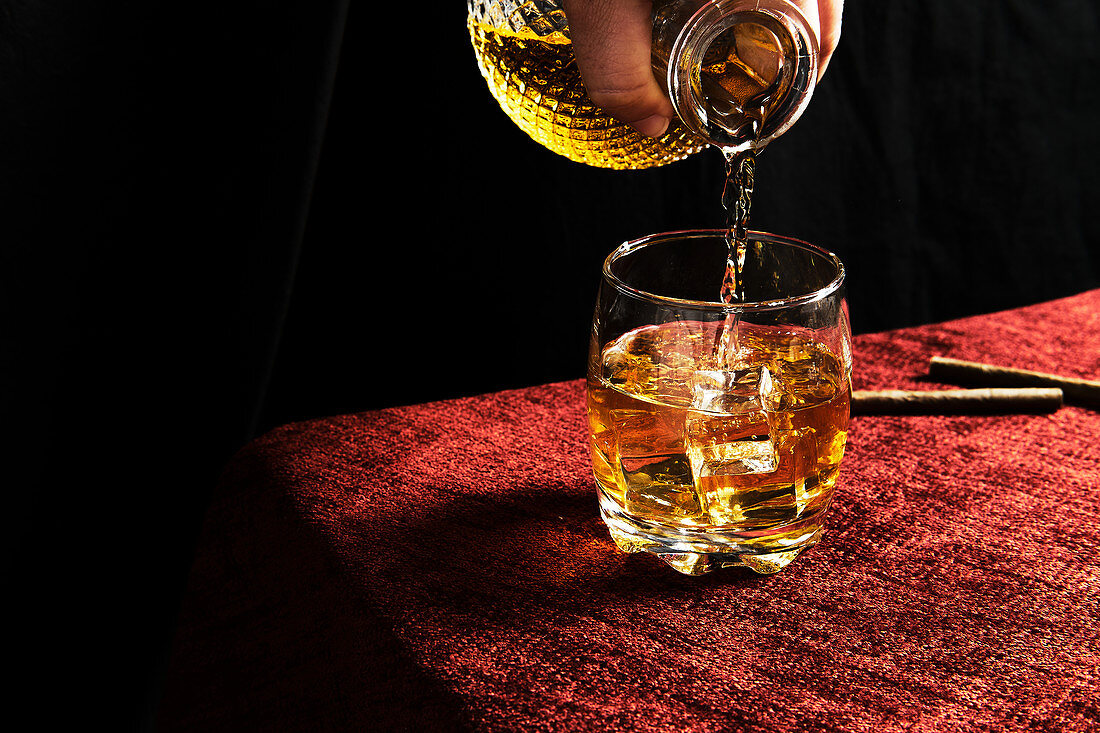 Anonymous person serving whiskey in a glass