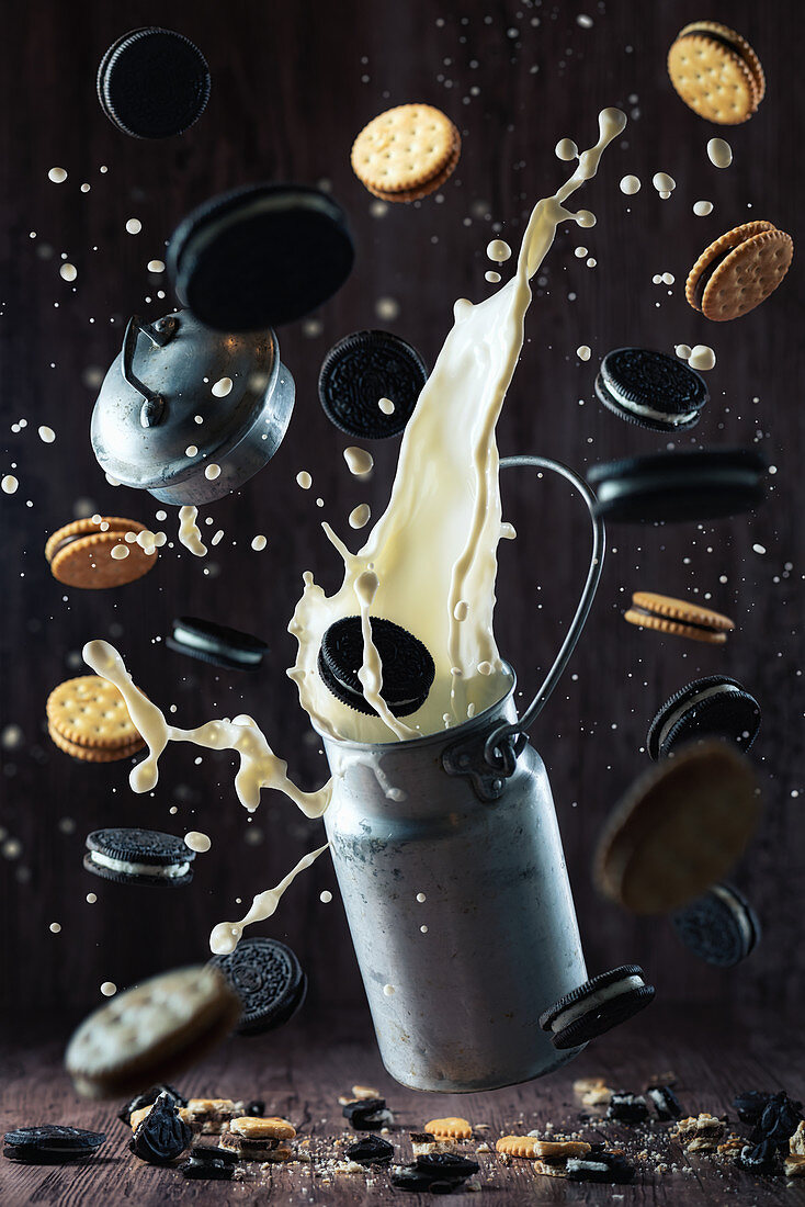 Various chocolate cookies and splashing milk from metal can creating chaos