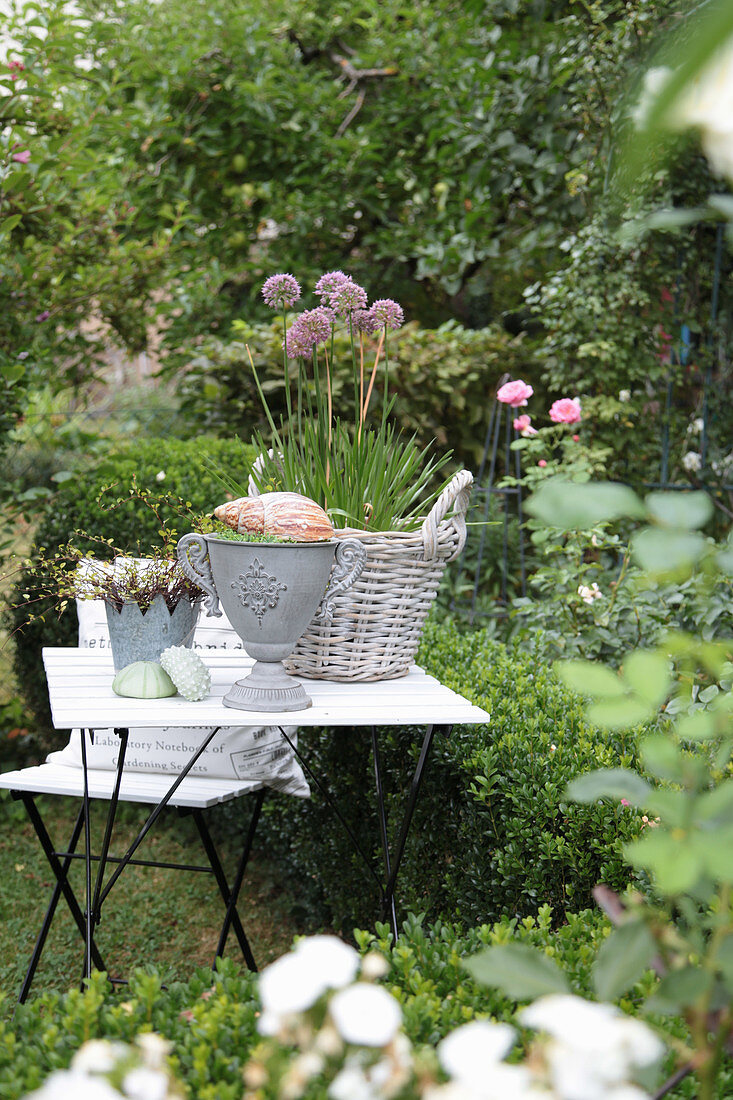 Decorative table with chive blossoms, amphora, zinc vase, and a seashell