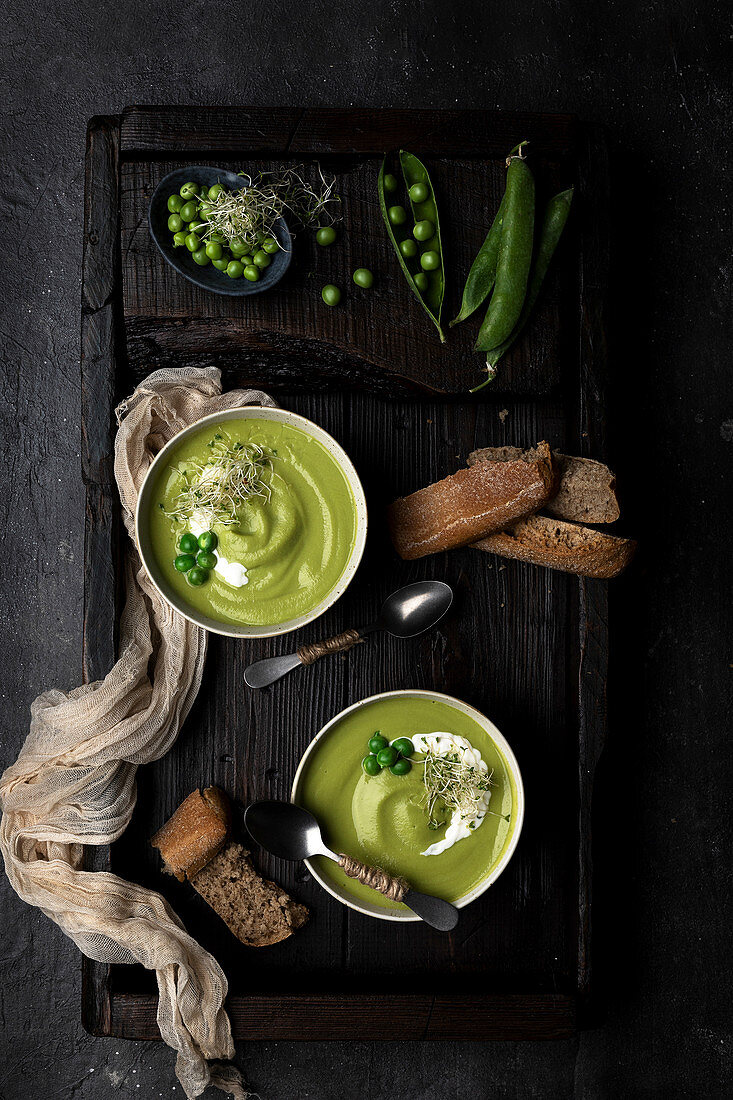 Pea cream placed on a wooden tray and dark surface, served with bread