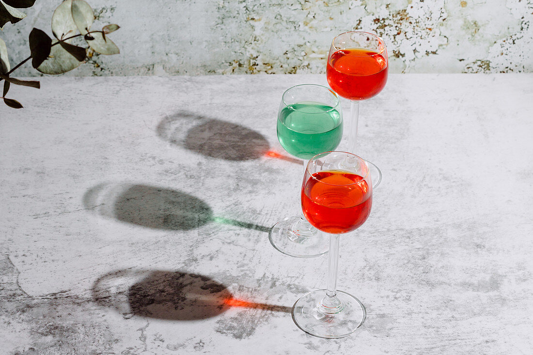 Glasses filled with colorful liquids put on concrete surface