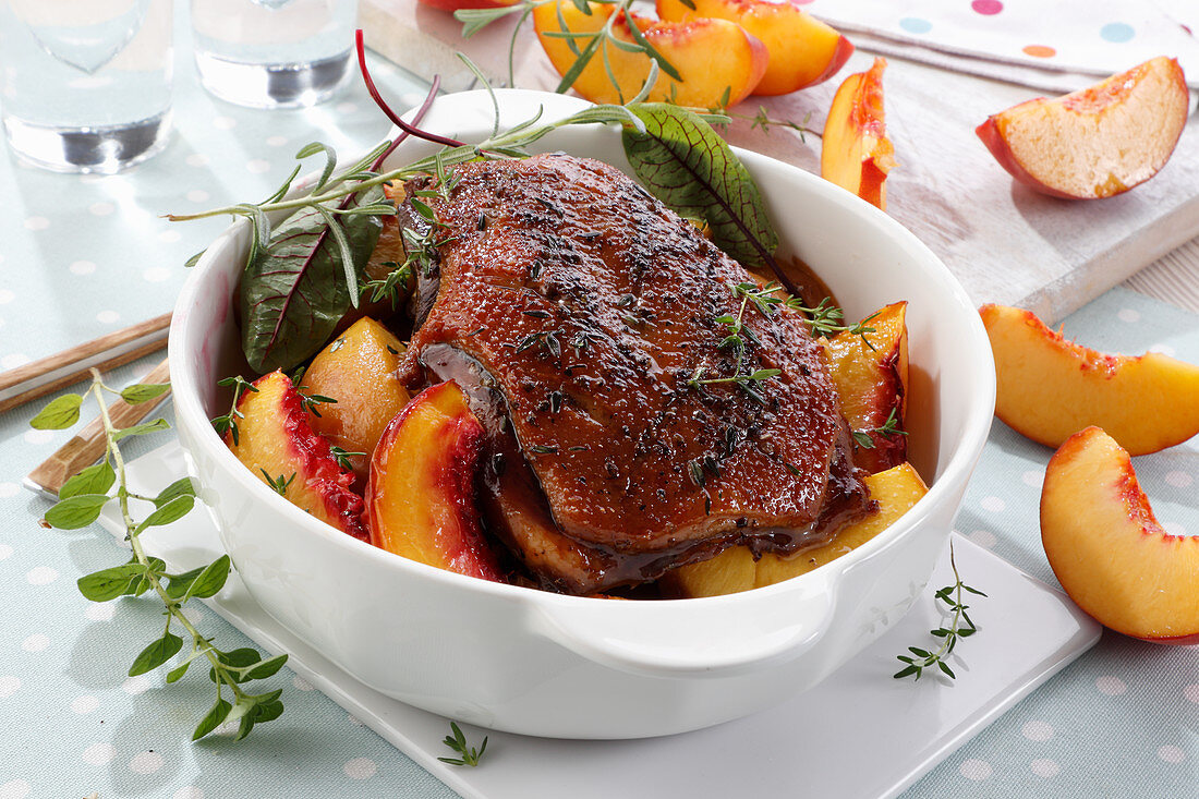 Baked goose breast in a sauce with pieces of peaches
