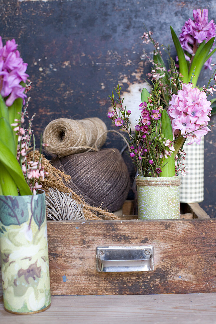 Sträuße aus Hyazinthen, Waxflower und Ginster an Schublade mit Schnur-Knäueln