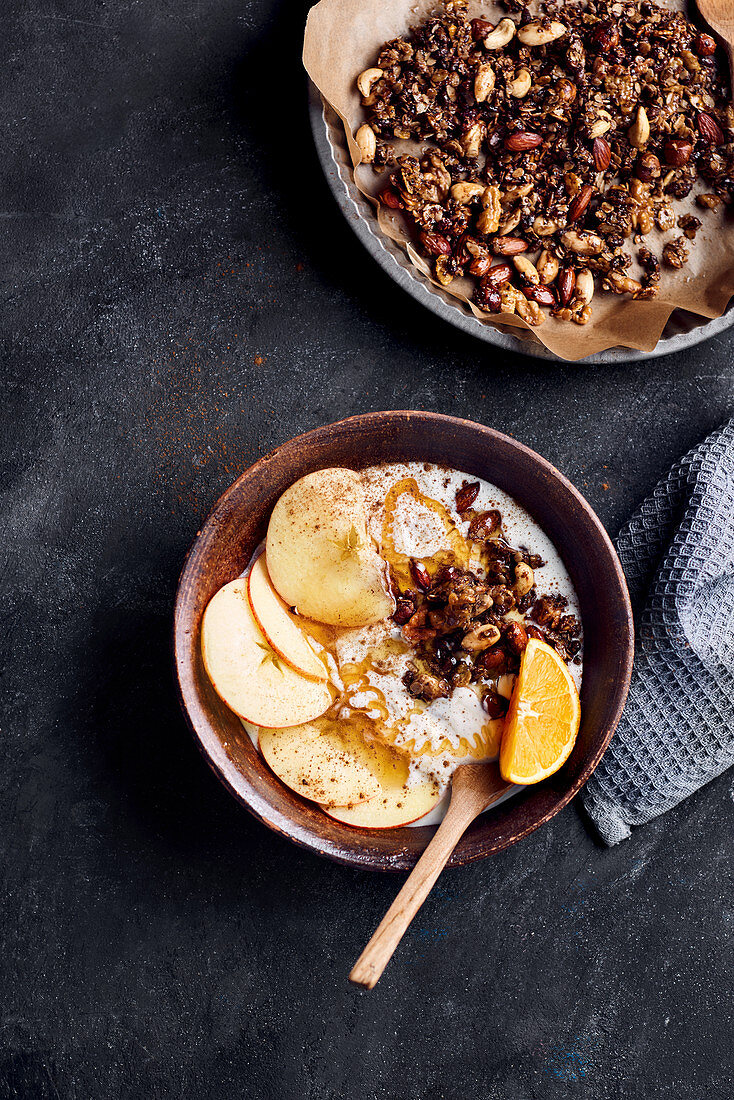 A breakfast bowl with yoghurt, apple, orange, granola, honey and cinnamon