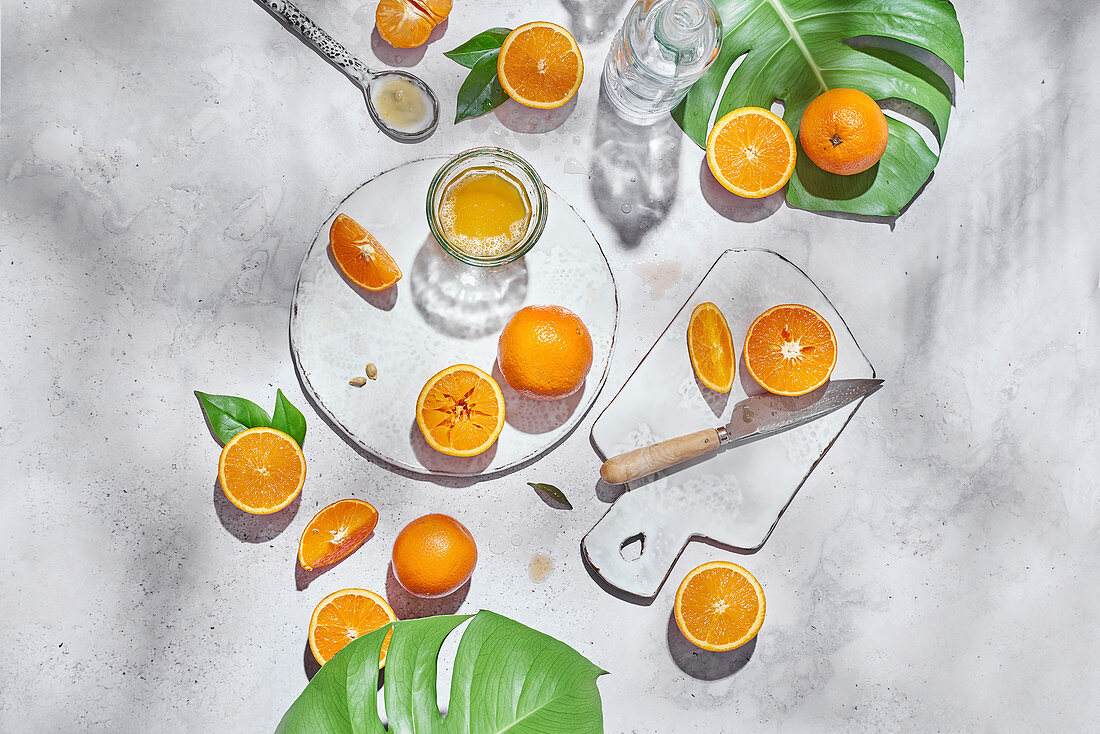 Whole and half of ripe oranges arranged on table with knife and glass with juice