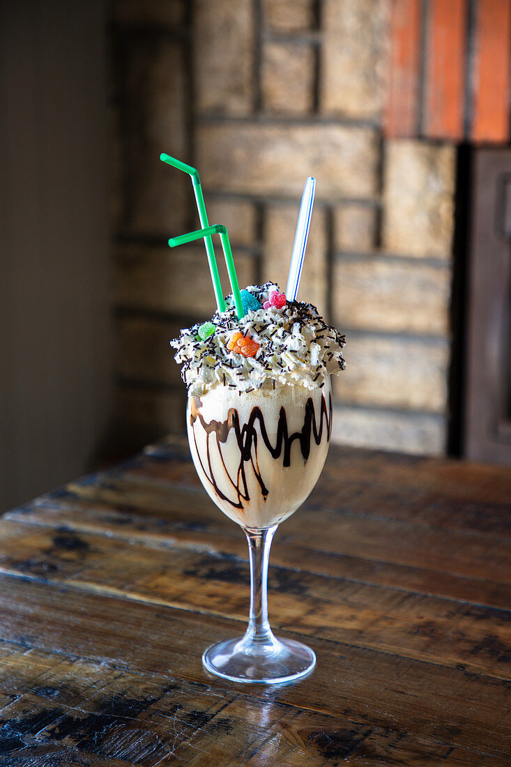 Sweet milkshake with chocolate syrup and whipped cream garnished with colorful sprinkles