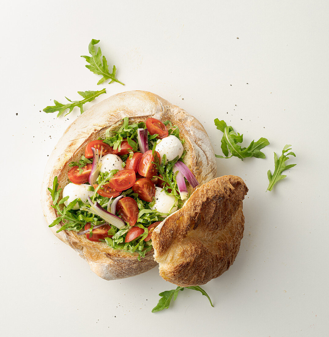 Tomaten-Mozzarella-Salat mit Rucola serviert im Brotlaib
