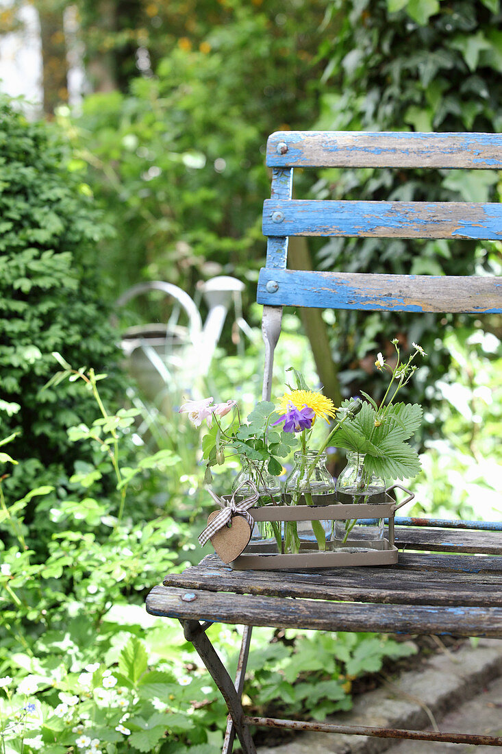 Deko mit Pflanzen und Blüten aus dem Garten auf altem Gartenstuhl