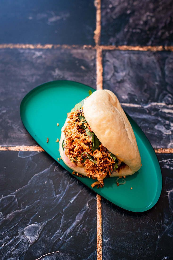 Bao filled with beeg short rib and garnished with crispy onion and toasted sesame seeds