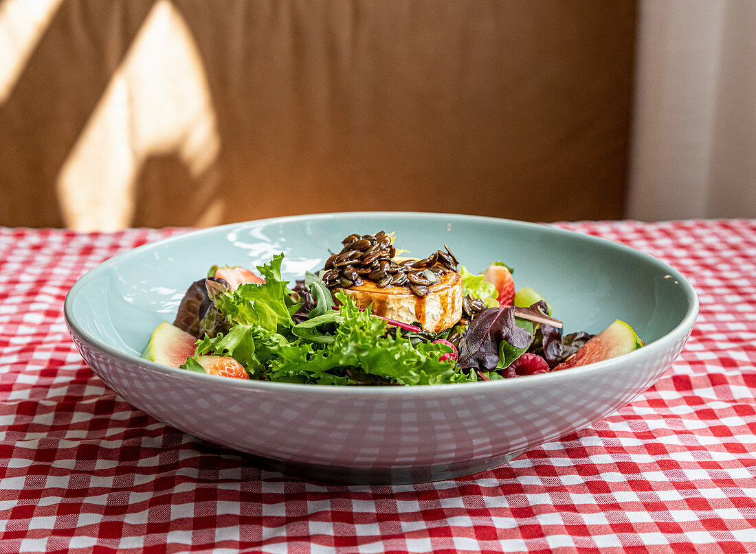 Goat roller cheese salad with various fruits and fresh greenery