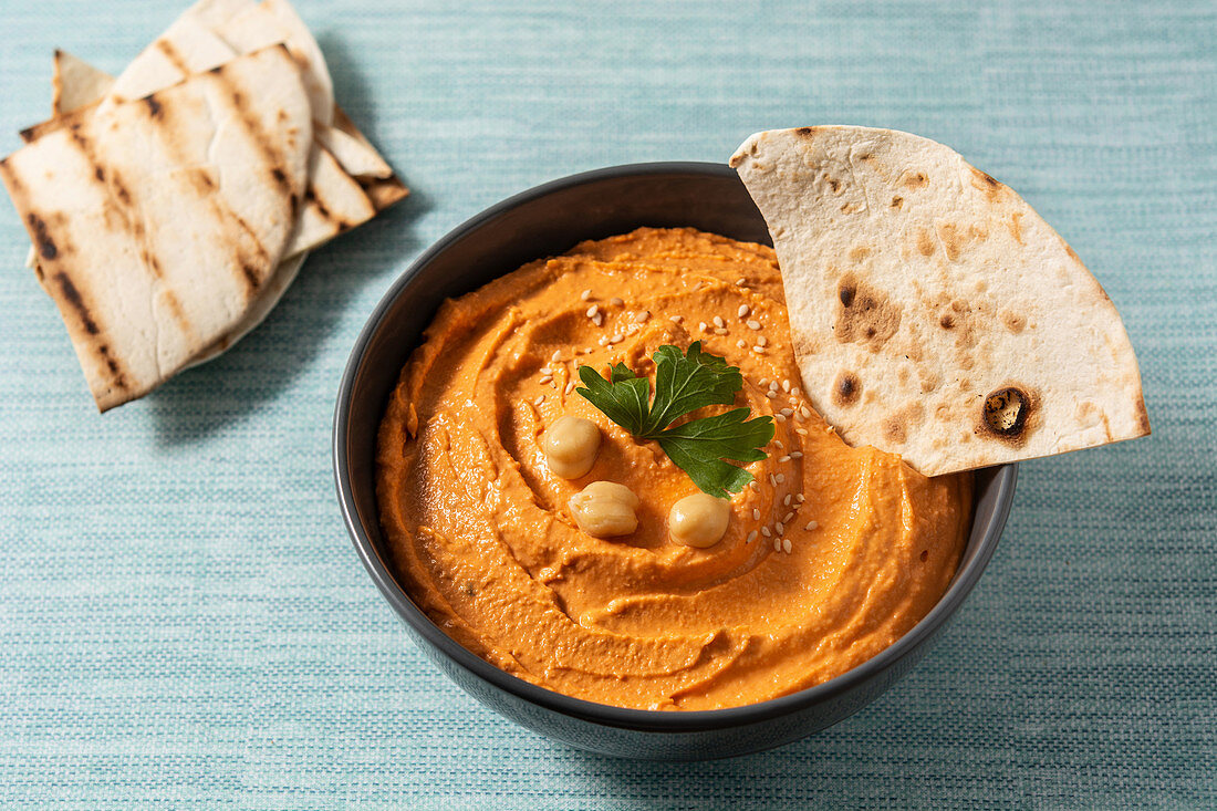 Pumpkin hummus in bowl on blue background