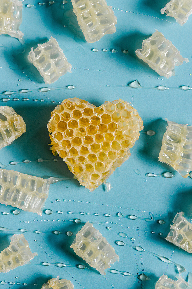 Heart shaped honeycomb with delicious honey on blue background