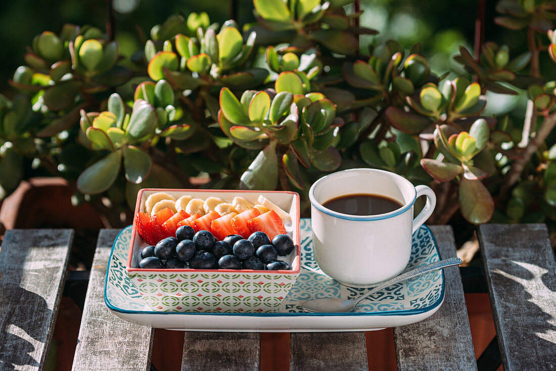 Frühstück mit Obst und Kaffee auf Gartentisch
