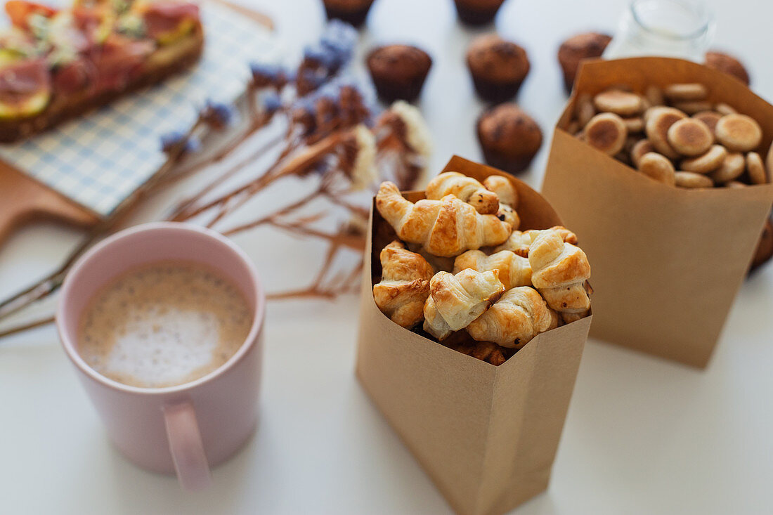 Paper bag with yummy sweet mini croissants and mug of hot aromatic coffee