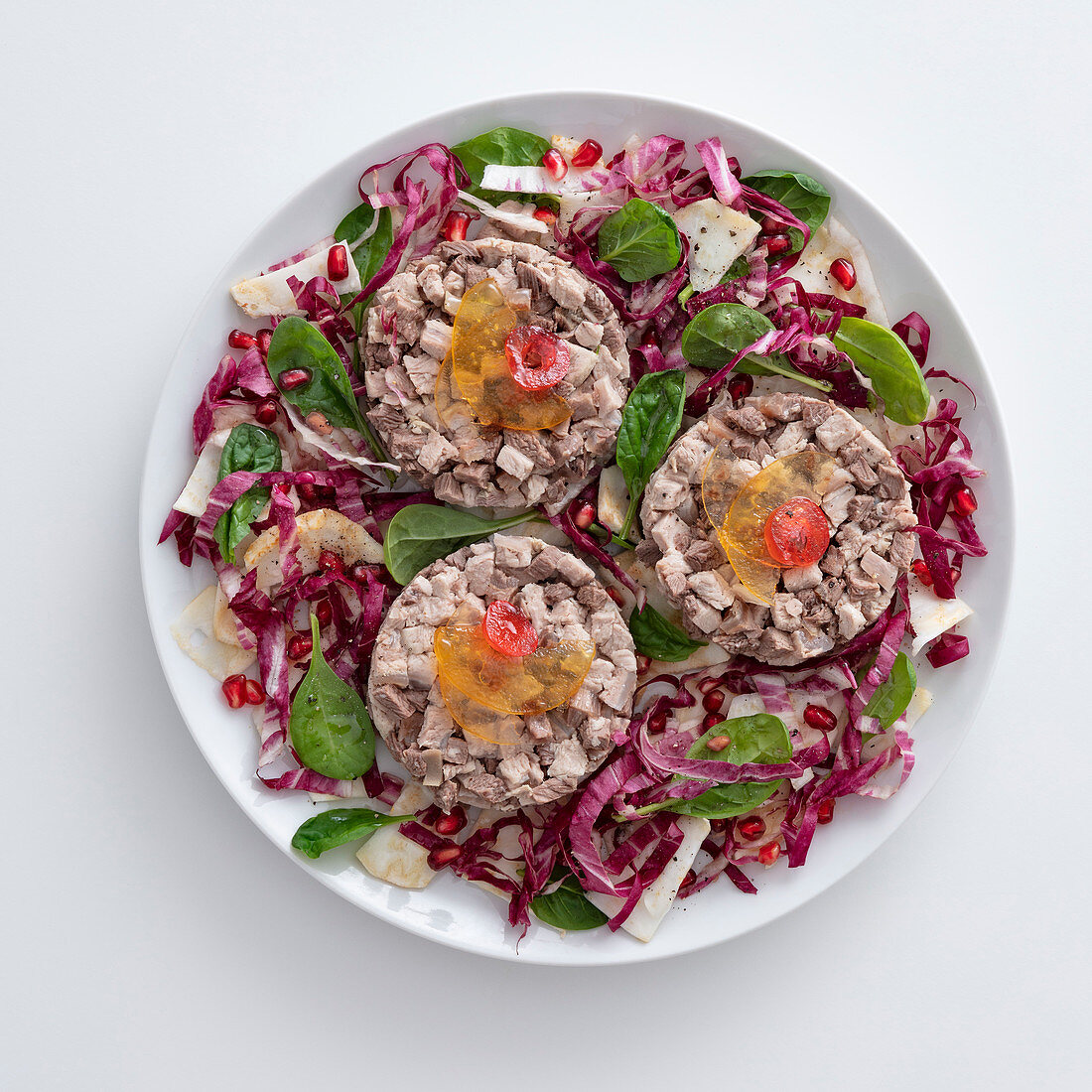 Boiled veal and beef on a bed of lettuce with pomegranate seeds