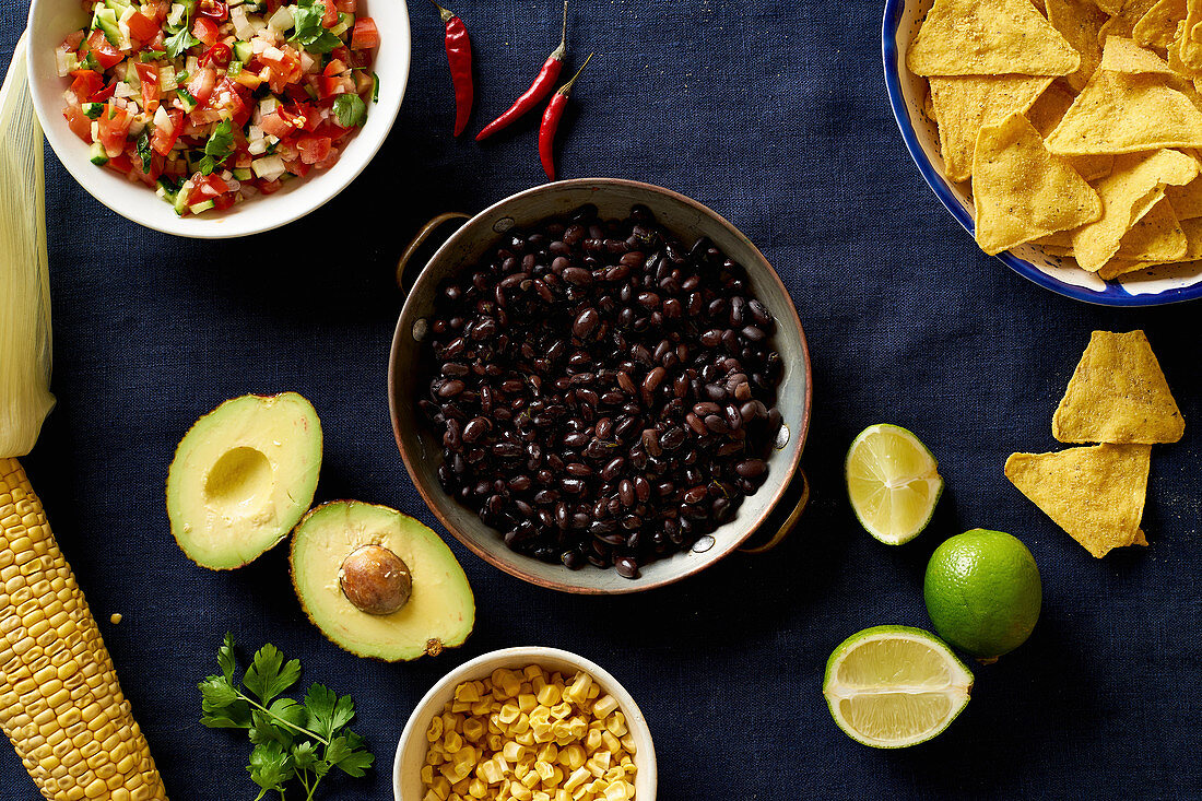 Zutaten für Chilaquiles - schwarze Bohnen, Tortillachips, Mais und Salsa