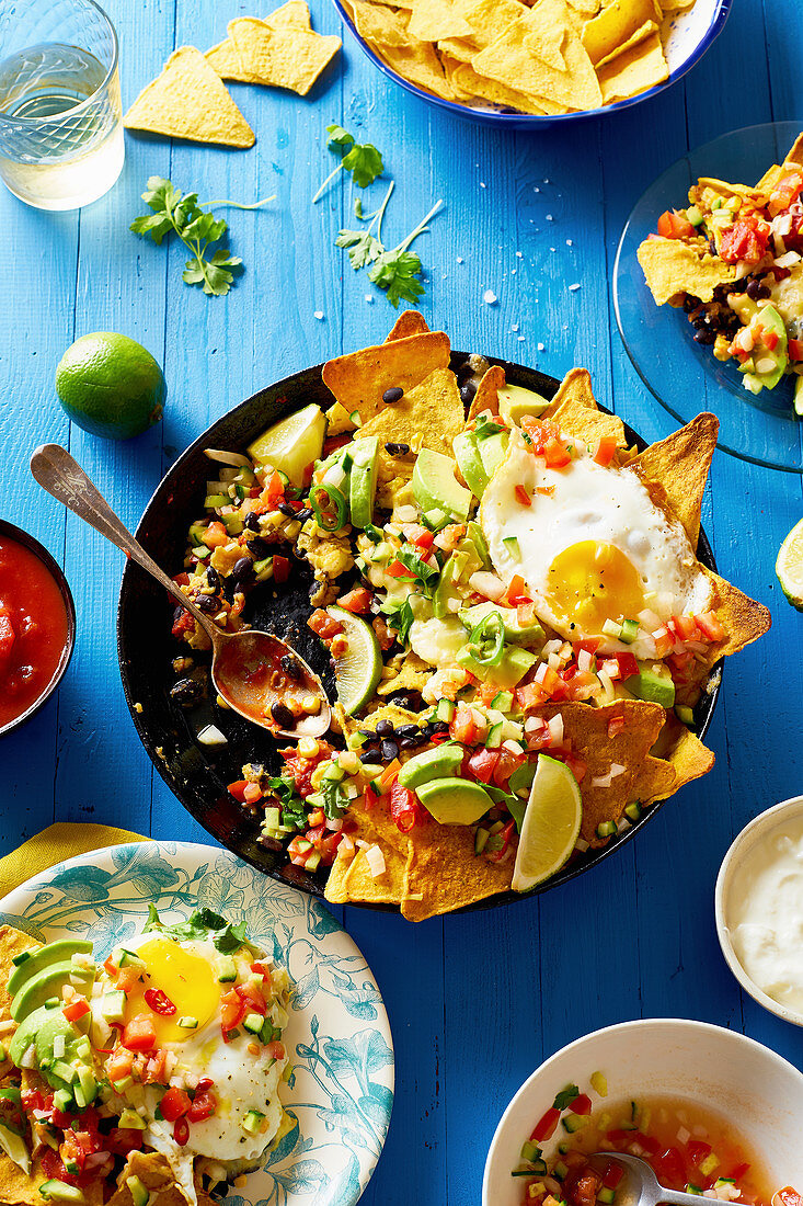 Chilaquiles mit schwarzen Bohnen, Mais, Tortillachips und Spiegeleiern