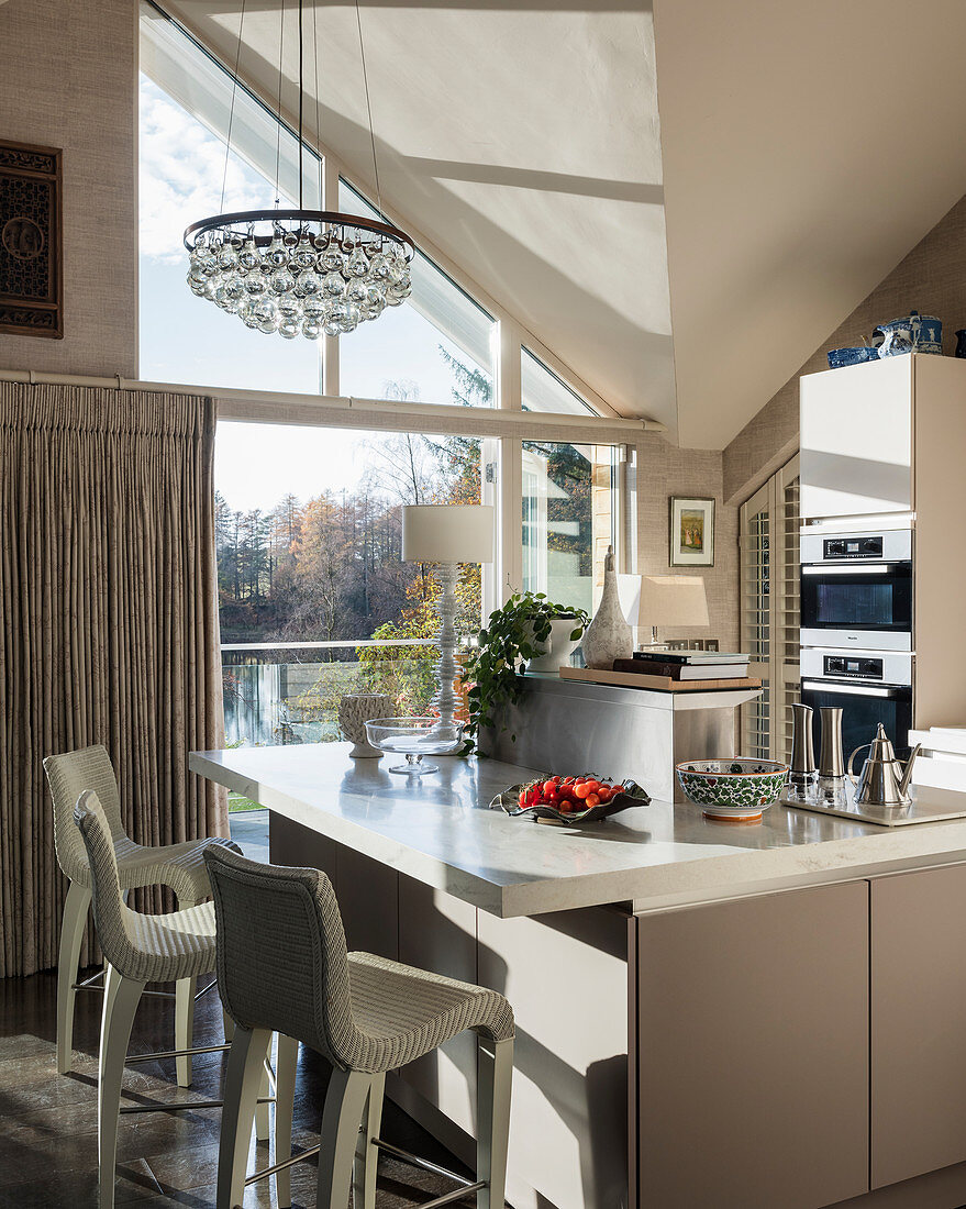 Barstools at island counter in modern, light-flooded kitchen