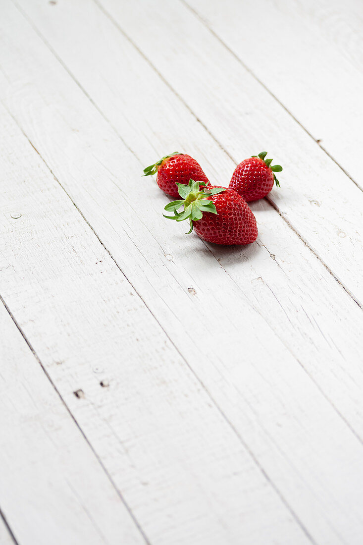 Fresh strawberries on white wooden plank surface