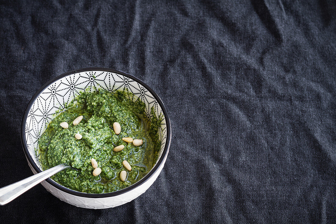 Green pesto with pine nuts in ceramic bowl