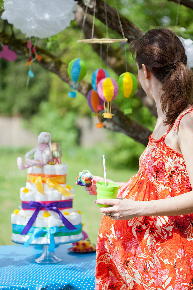 Pregnant woman in front of a diaper cake at a baby shower