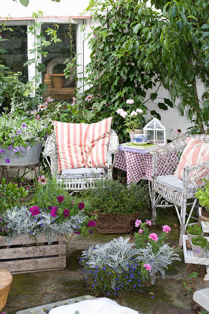 Sommerterrasse mit Korbmöbel, Balkonblumen und Kübelpflanzen