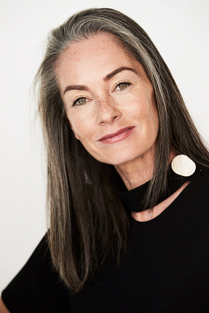 A woman with salt-and-pepper hair wearing a choker and a black blouse