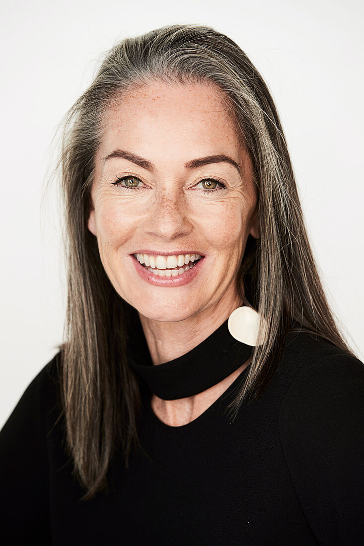 A woman with salt-and-pepper hair wearing a choker and a black blouse