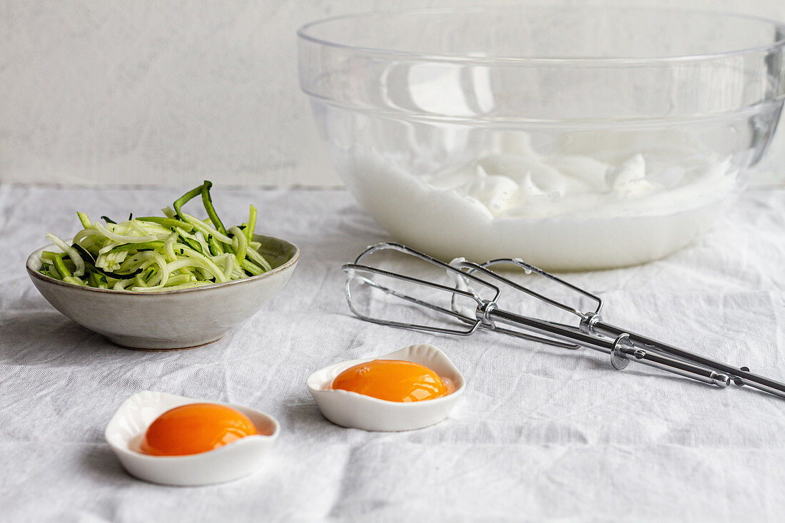 Making cloud eggs; egg yolks in small bowls, beaten egg whites and vegetables