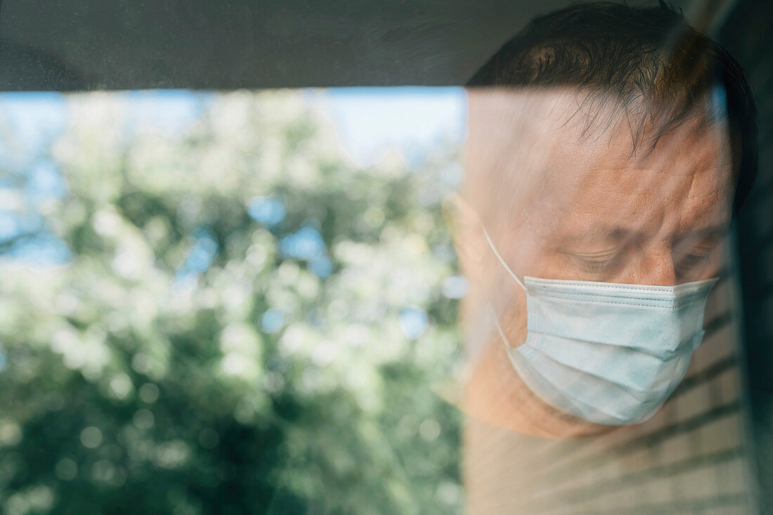 Worried man with protective face mask in self-isolation