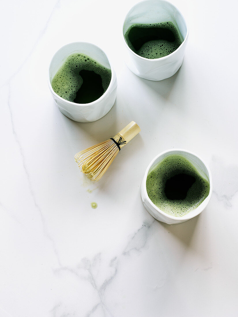 Three cups of Matcha tea with whisk