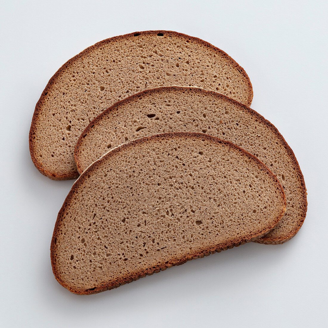 Three slices of rye bread on a white surface