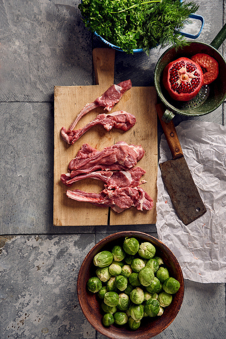 Lamb chops on a wooden surface next to Brussels sprouts
