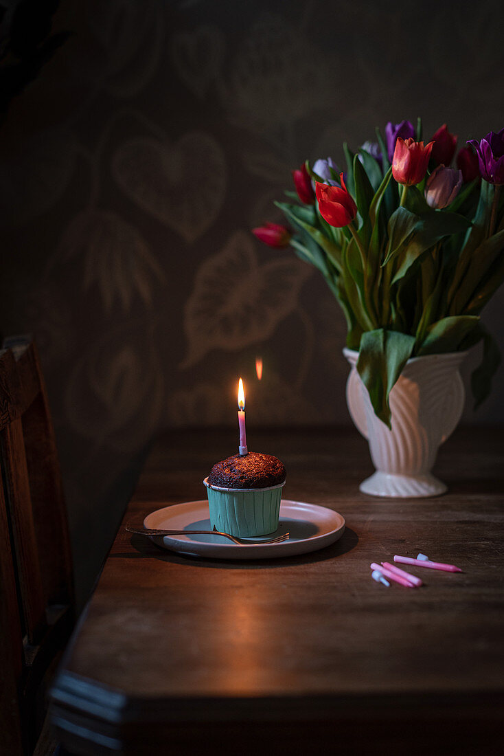 Schokoladen-Cupcake zum Geburtstag mit brennender Kerze