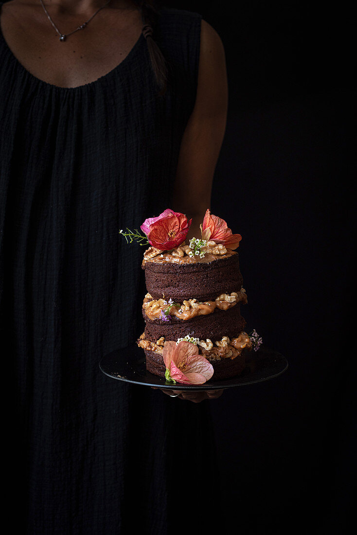 Chocolate naked cake with cream, walnuts and edible flowers