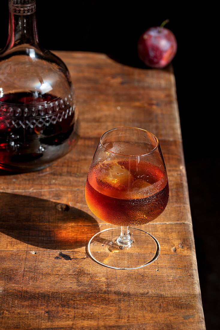 Glass of cognac with ice cubes and decanter