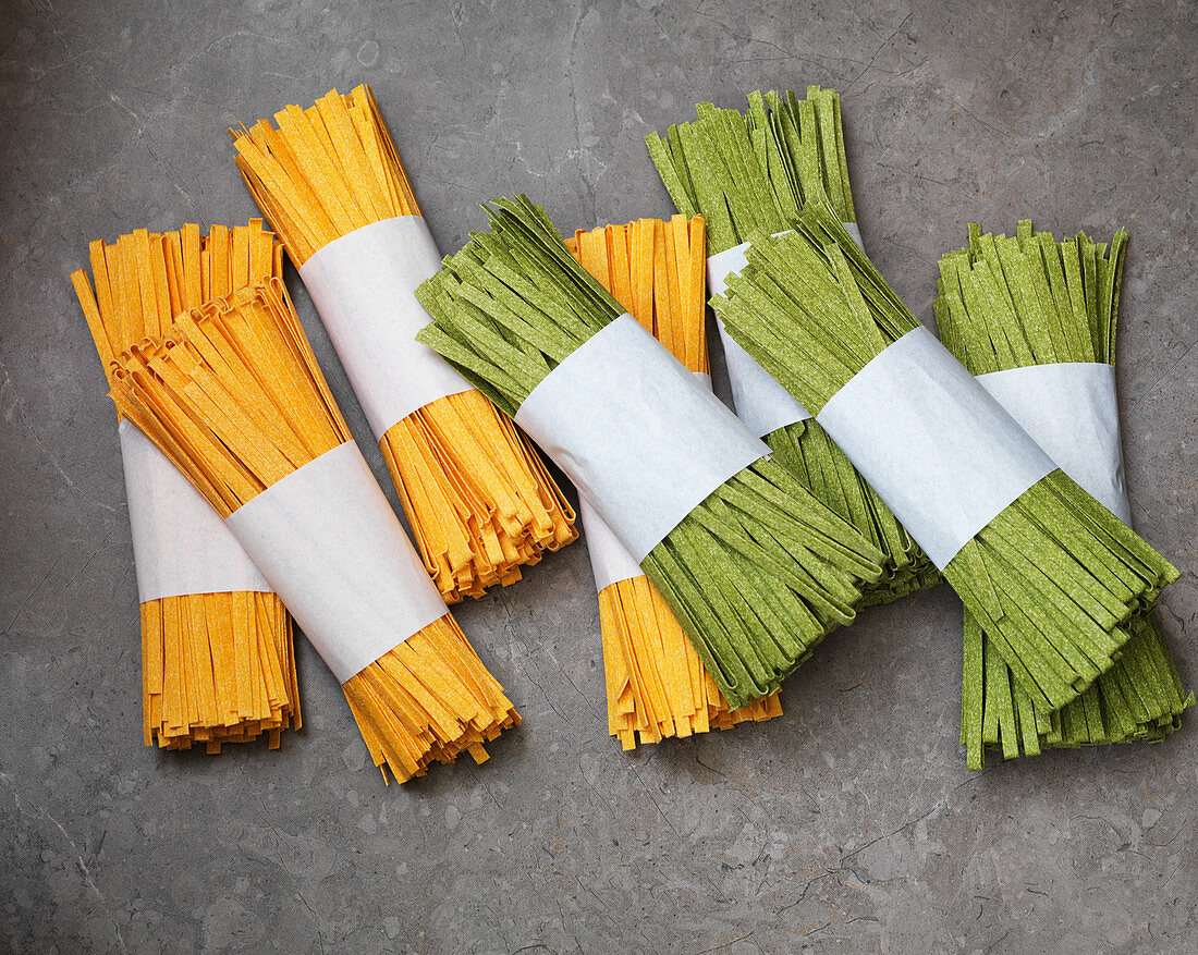 Uncooked yellow and green tagliatelle in bundles