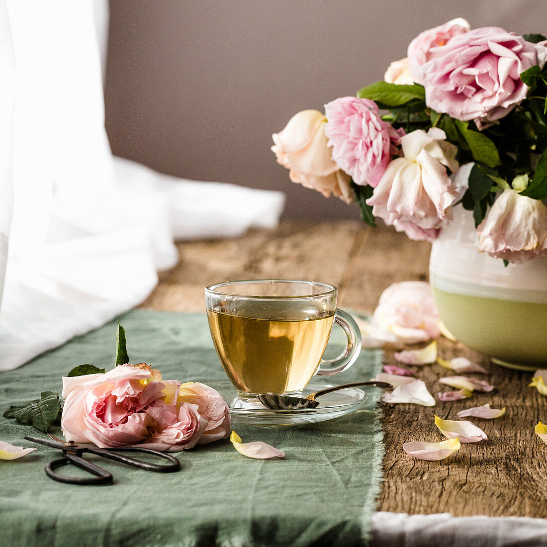 Eine Tasse Kräutertee neben Rosenstrauß