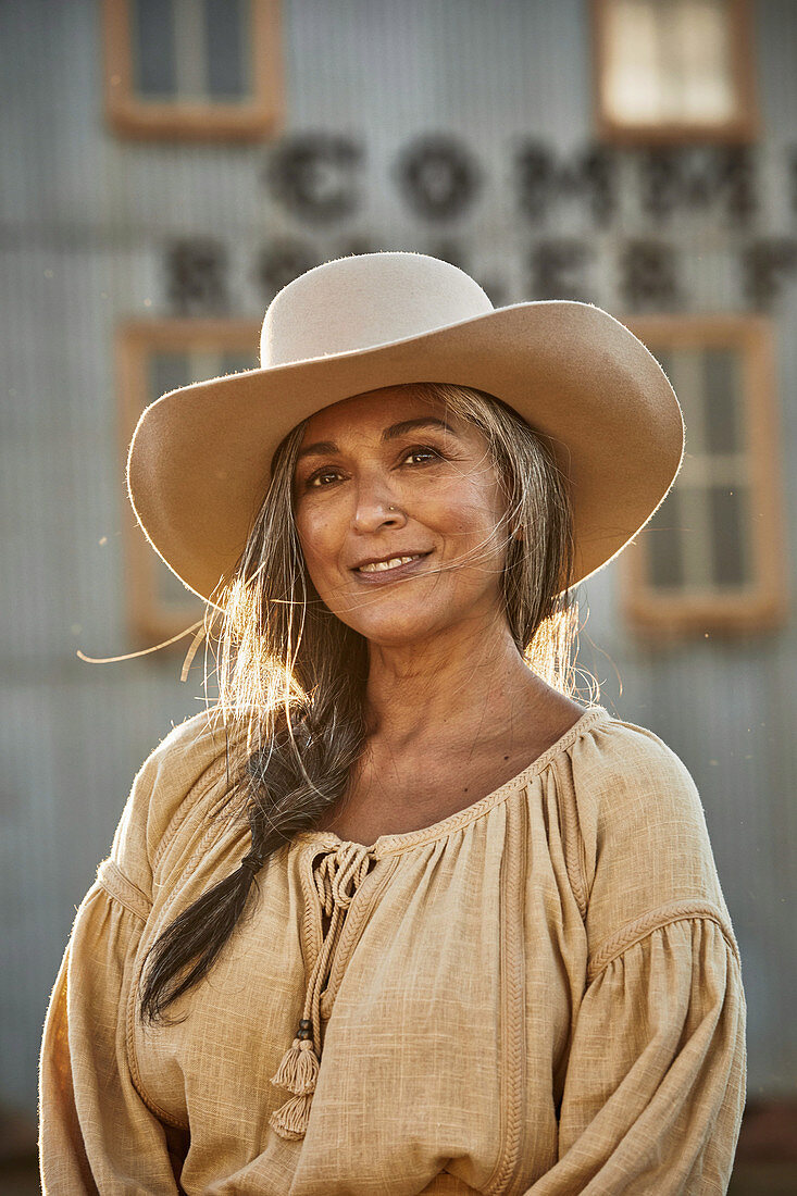 A grey-haired woman wearing a hat and a linen blouse