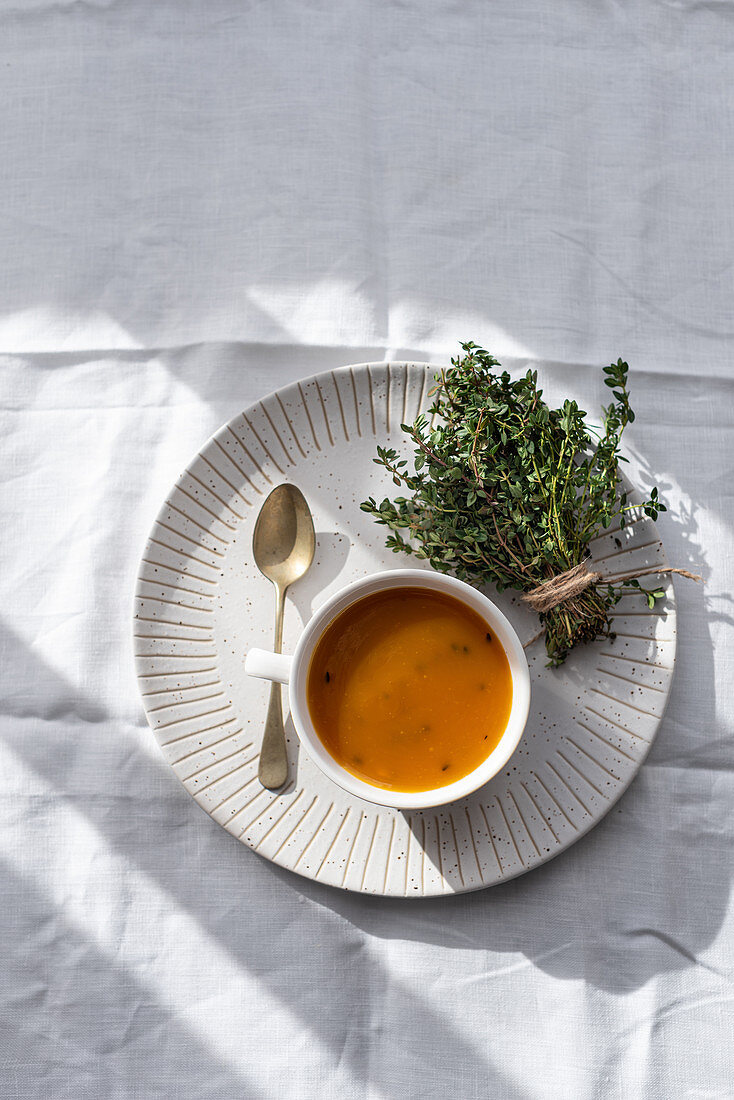 Kürbissuppe in Suppentasse mit Kräutersträusschen