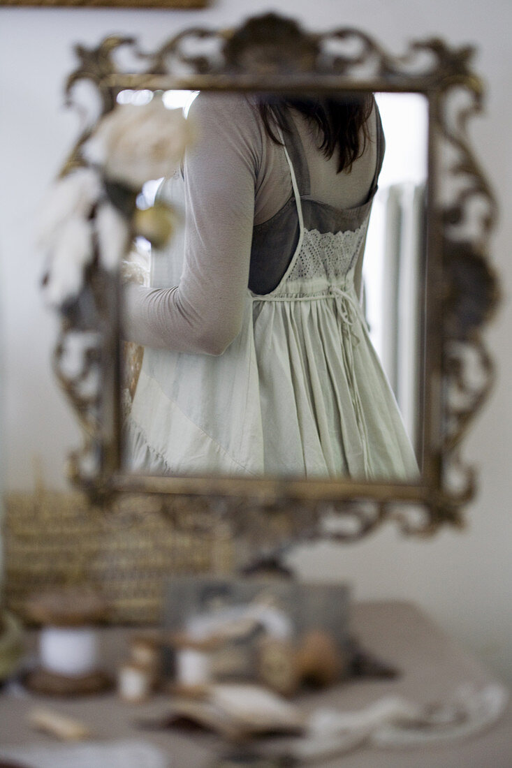 Frau mit nostalgischem Kleid im verzierten Standspiegel