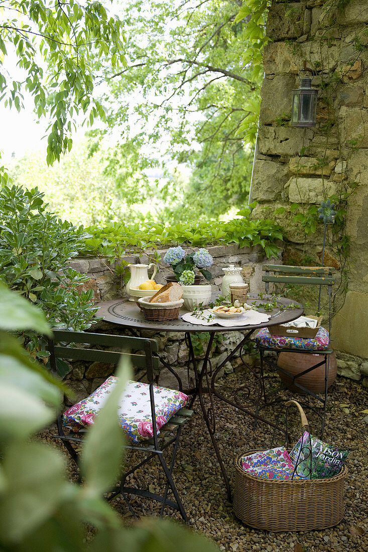 Gedeckter Tisch im verwunschenen Garten mit Natursteinmauer