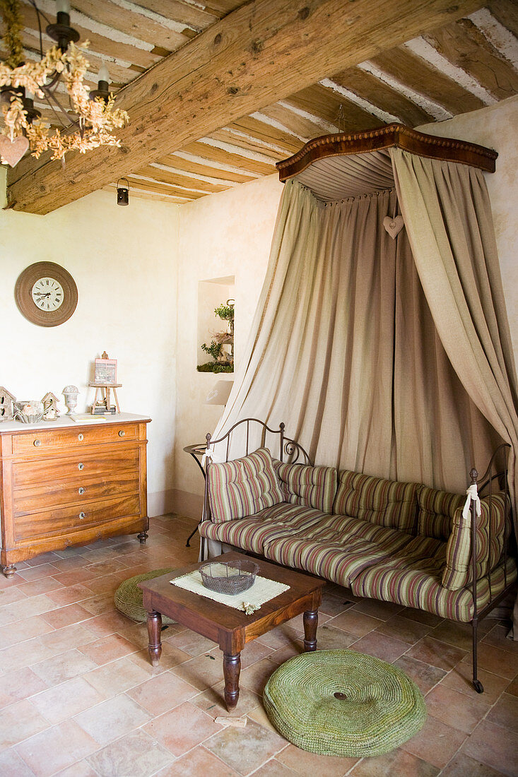 Metal day bed with canopy on a terracotta tiled floor