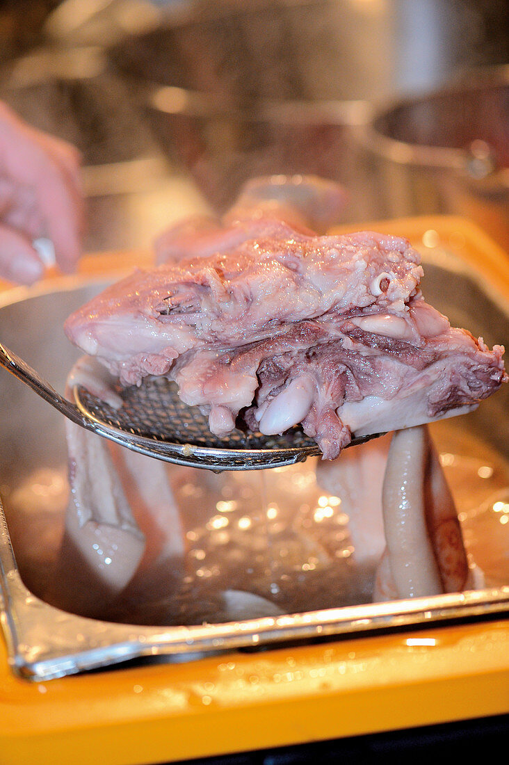 Sausages being made: cooked meat being removed from broth